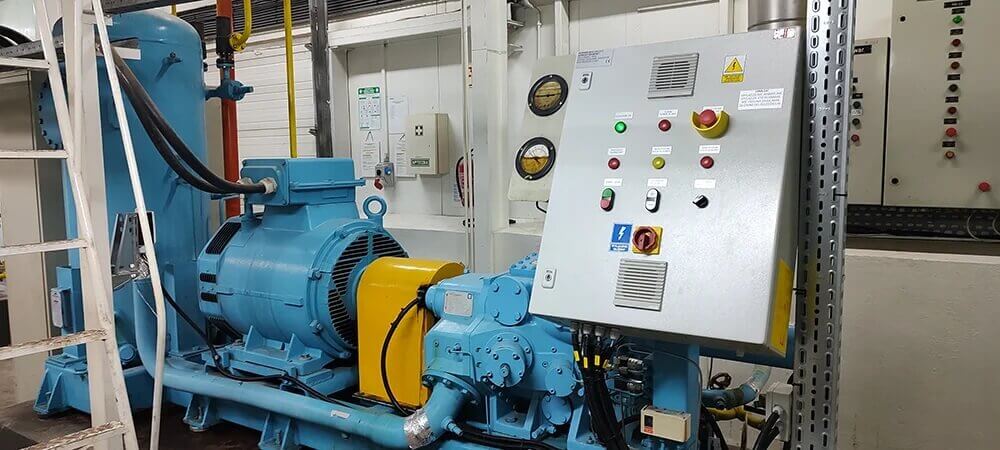 Na zdjęciu widoczna je przemysłowa sprężarka chłodnicza z panelem sterowania, manometrami i automatyką kontrolną. 