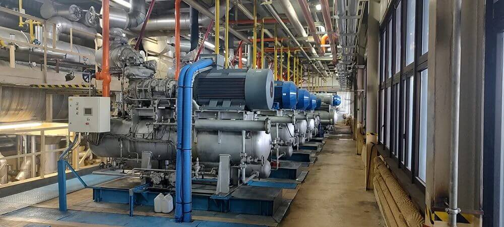 Zdjęcie przedstawia przemysłową instalację chłodniczą z agregatami sprężarkowymi i automatyką sterowania.